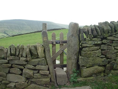 A narrow gate in a dry stone wall leads to the field beyond.