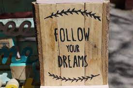A wooden sign saying "Follow Your Dreams."
