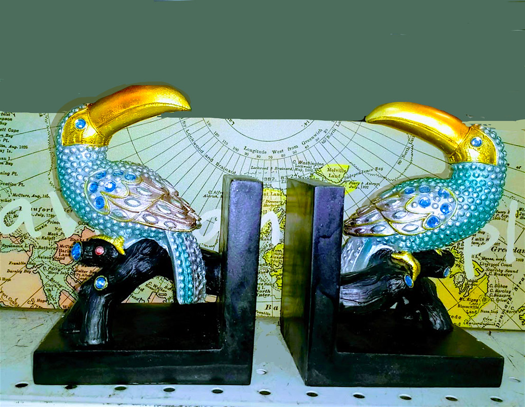 Two resin bookends, resin toucans in turquoise and gold.