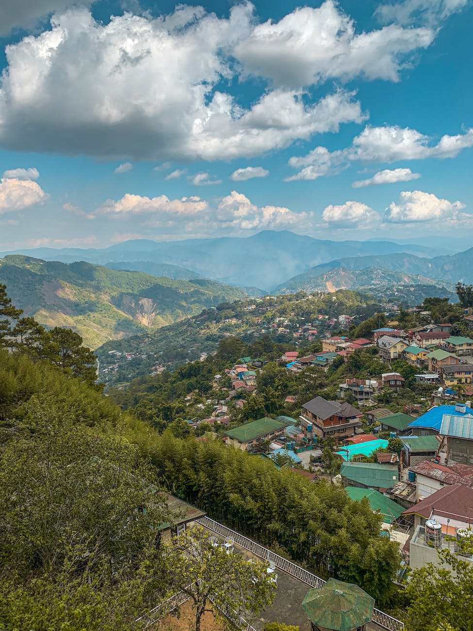 A view of a village and the countryside beyond fron a mountain top.