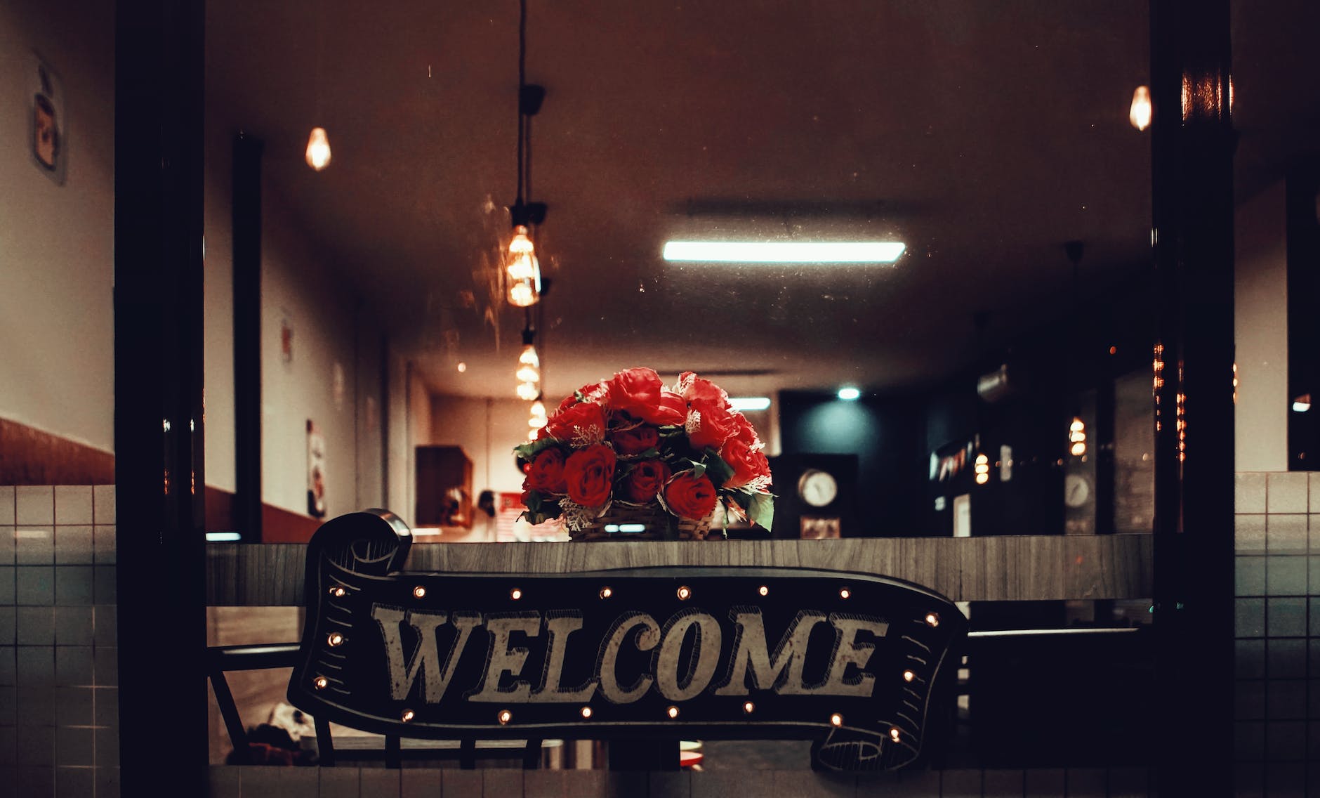 A sign saying Welcome hangs in fromt of a table on which is a display of roses.