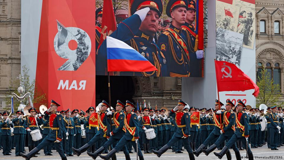 Soldiers, carrying both the flags of Russia and the former Soviet Union. march through Moscow.