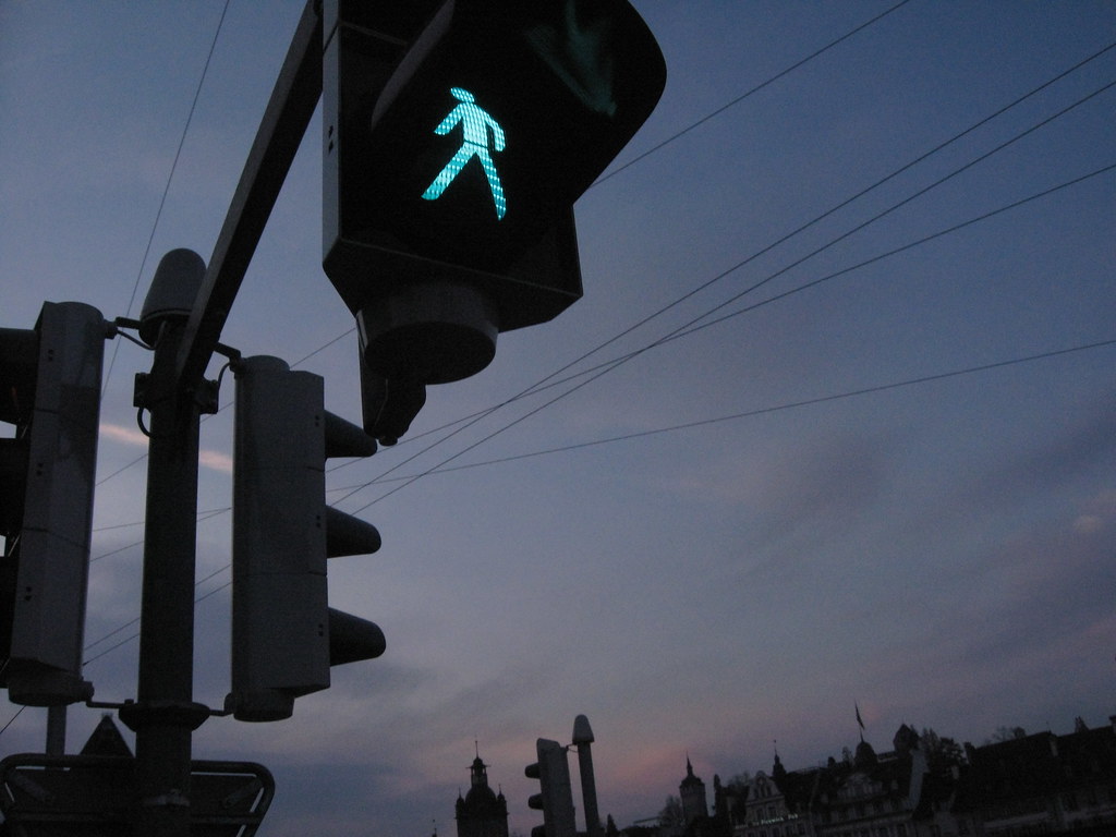 A green man pedestrian walk light against a darkening sky.