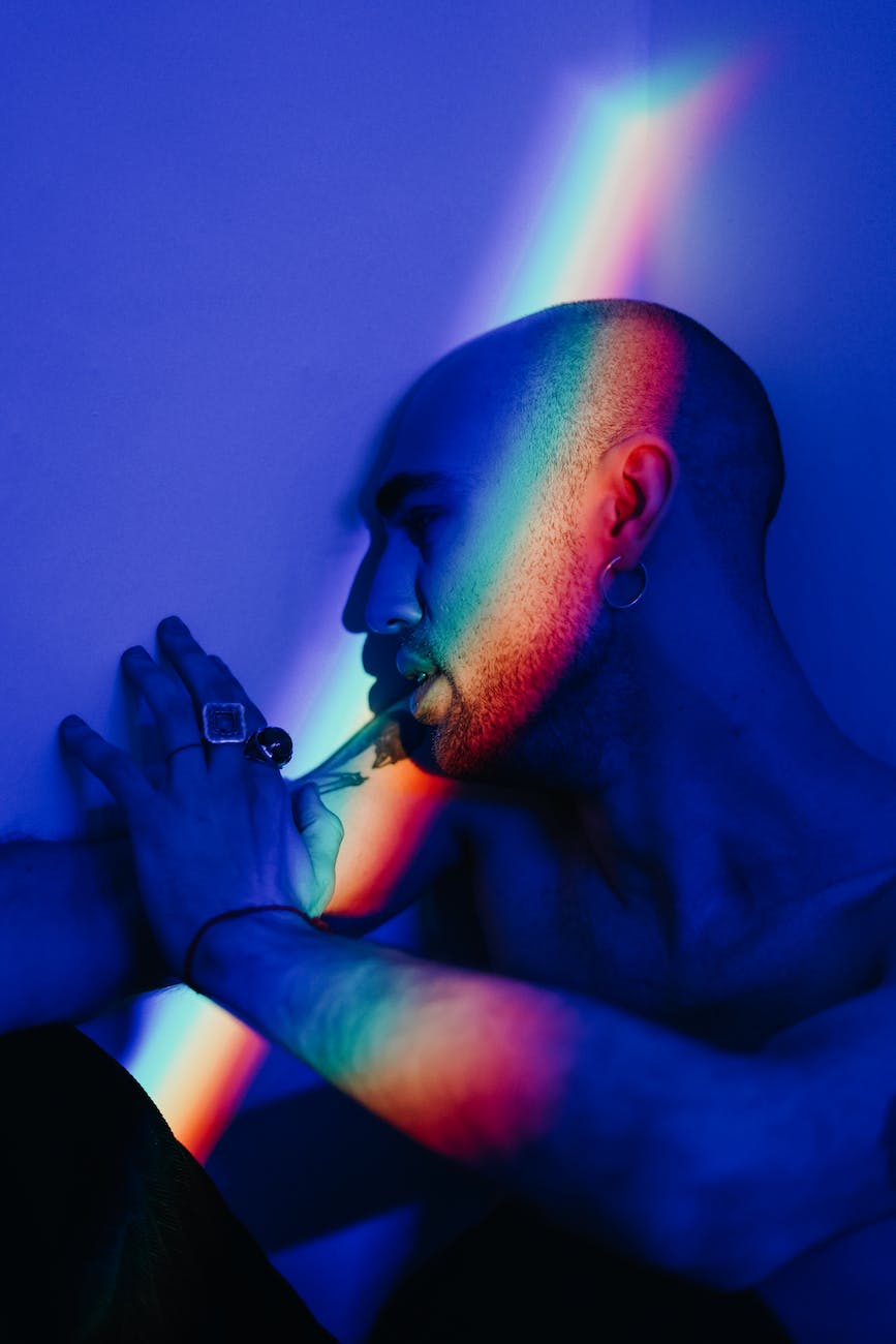 A man lies across a spectrum of light projected on a wall.
