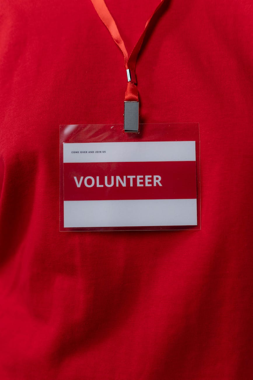 A lanyard with a badge saying volunteer hangs in front of a red shirt.