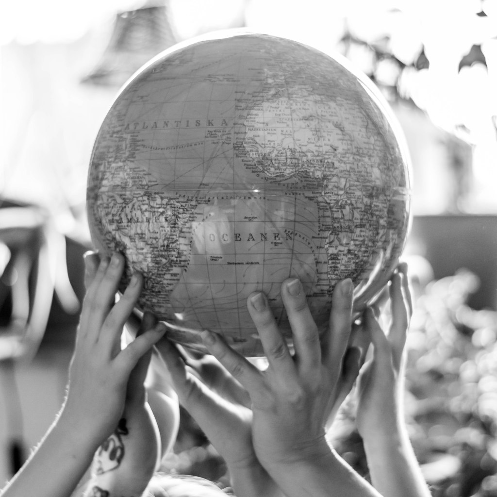 Children's hands. in different skin tones, hold up a globe.