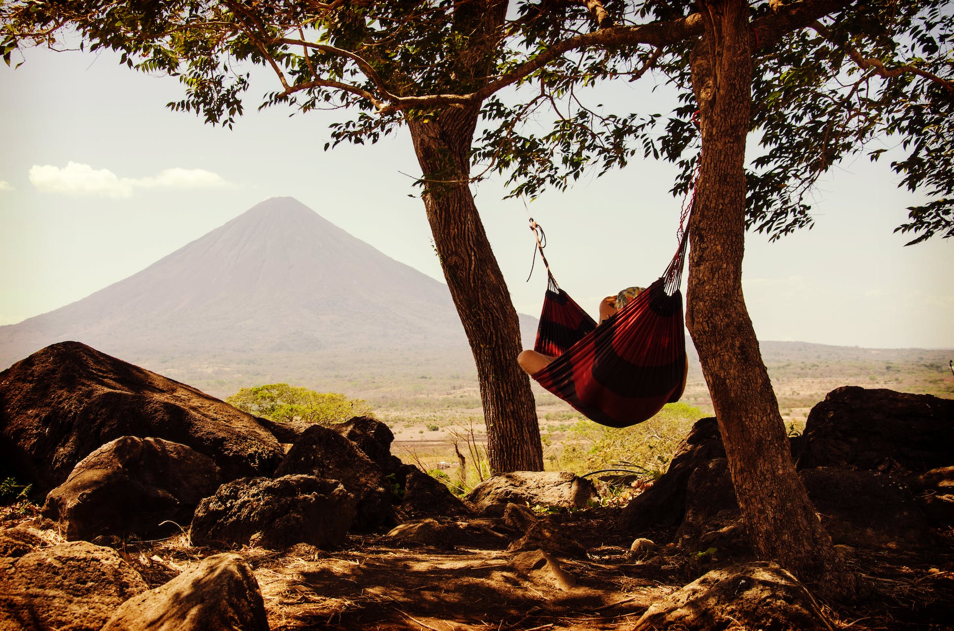 An occupied hammock is slung between two trees with Mount Kilimanjaro in the background.