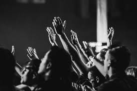 Greyscale image of people raising their hands in praise to God.