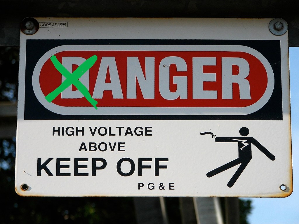 A warning sign with the letter D in danger crossed out so that it reads. "Anger, high voltage above, keep off."